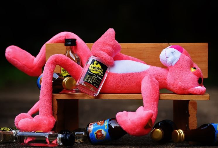Pink Panther-Figur liegt auf Bank mit vielen kleinen Alkoholfläschchen