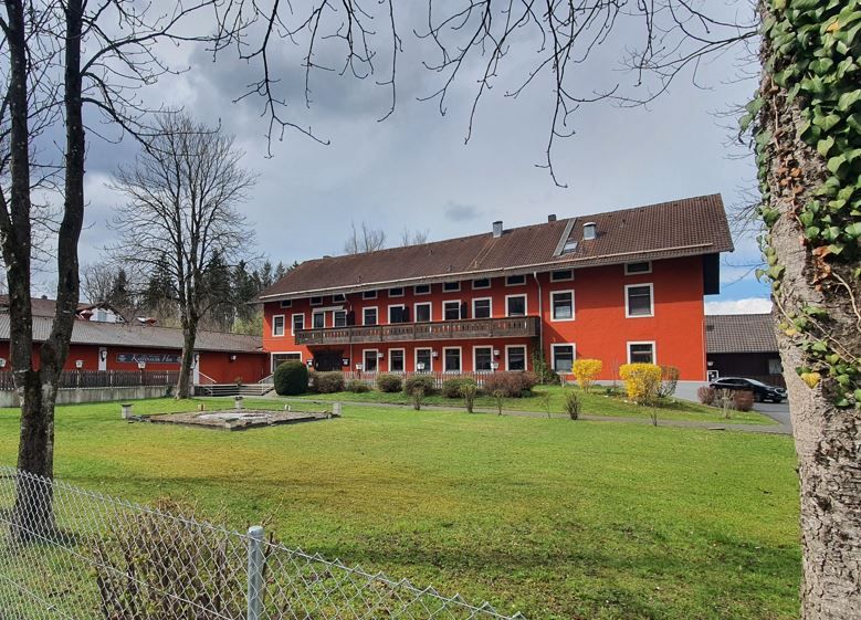 Gasthaus mit rötlicher Fassade mit großer Rasenfläche davor