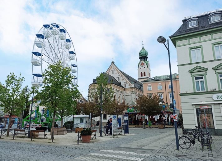 Blick auf Ludwigsplatz in Rosenheim mit Kirche St. Nikolaus und davor das Riesenrad. Darüber blau-weisser Himmel