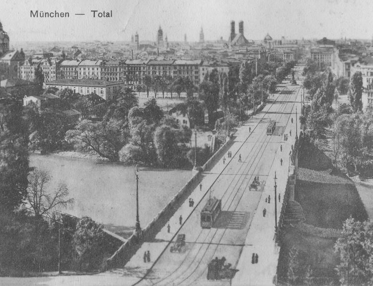historische Aufnahme aus dem Jahr 1928, schwarz-weiss von der Stadt München. Blick auf eine Straße mit Straßenbahn, Bäume, Häuser