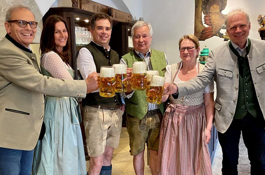 Zwei Damen und vier Herren stoßen mit Bier an