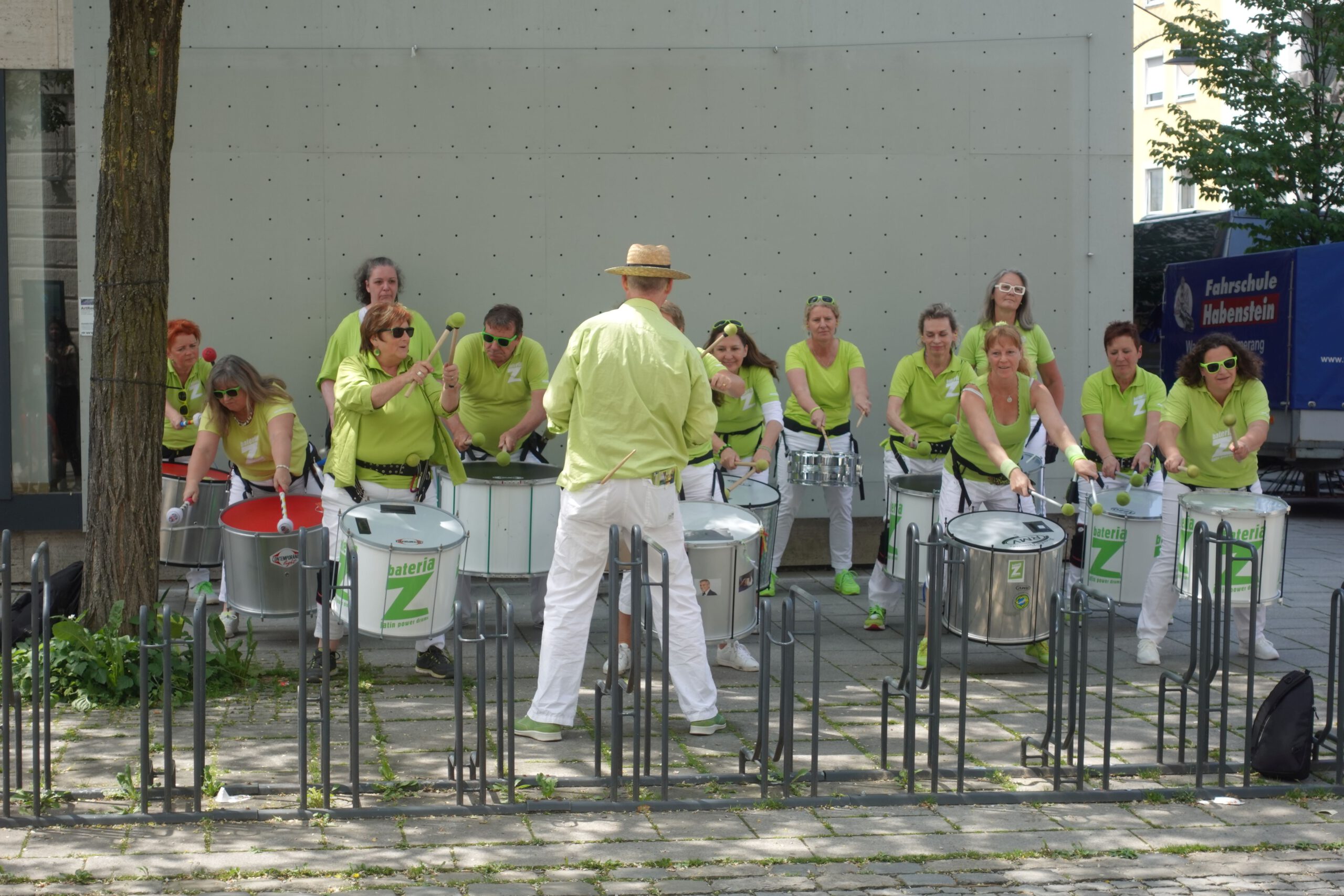 Trommelgruppe bei ehemaligen Sport-Karstadt mit grünen T-Shirts und weißen Hosen