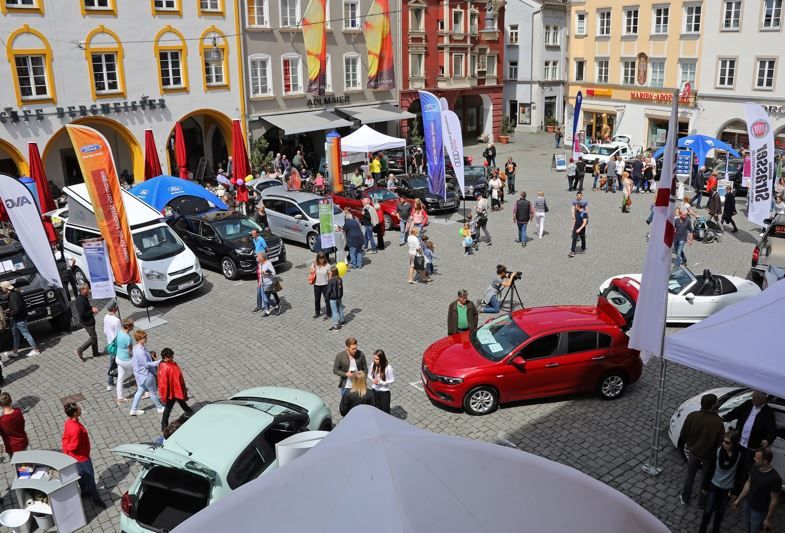 Blick auf Max-Josefs-Platz in Rosenheim mit Menschen, Autos und Infoständen