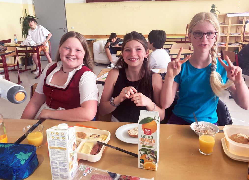 Drei Schülerinnen am Schultisch in der Privatschule Dr. Kalscheuer in Traunstein mit Fruehstück Fairtrade