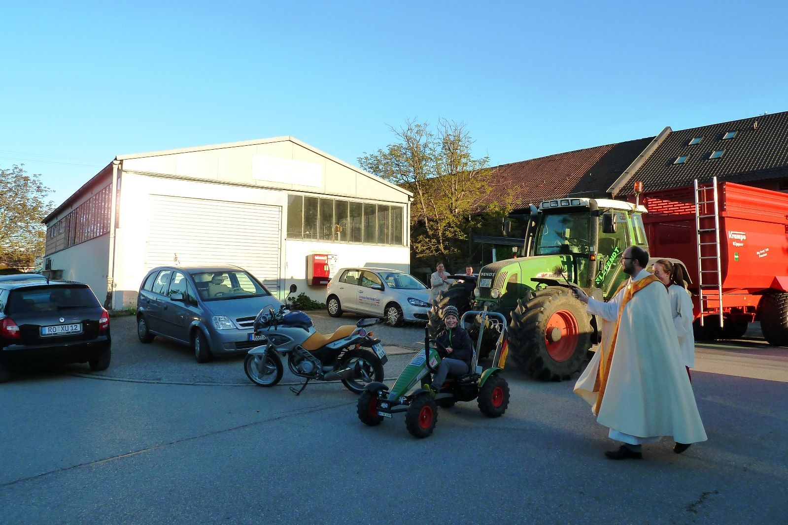 Pfarrer bei Segnung von großem Traktor und Spielzeugtraktor