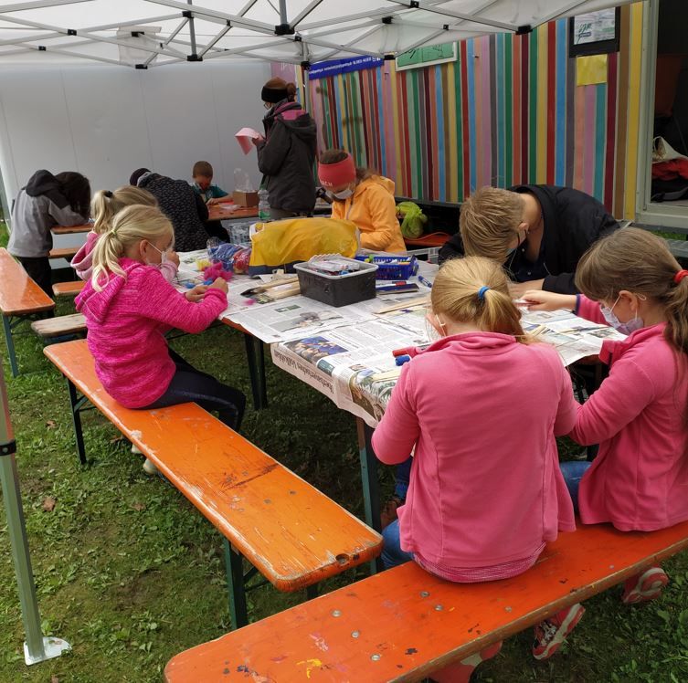 Spielstadt Mini Ro am Jugendreizeitgelände am Happingerausee in Rosenheim: Kinder basteln an Biertischen