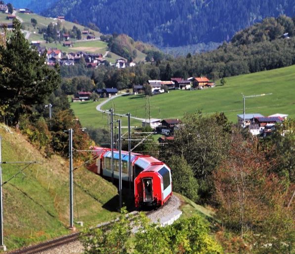 Roter Zug schlängelt sich durch Alpenlandschaft