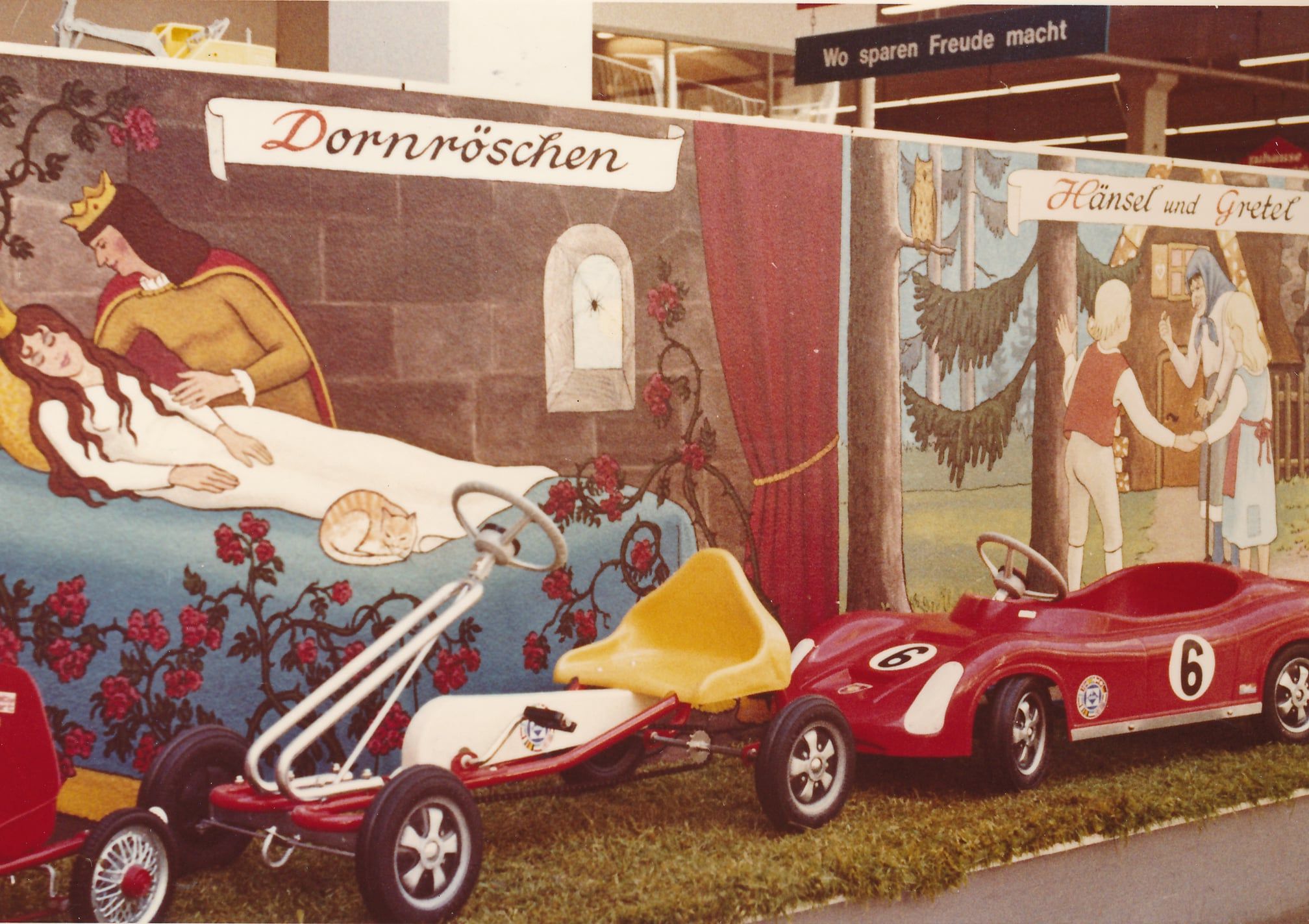 Blick zum Kinderland mit einigen Kinderfahrzeugen und Märchenkulisse aufgemalt auf Holzwand