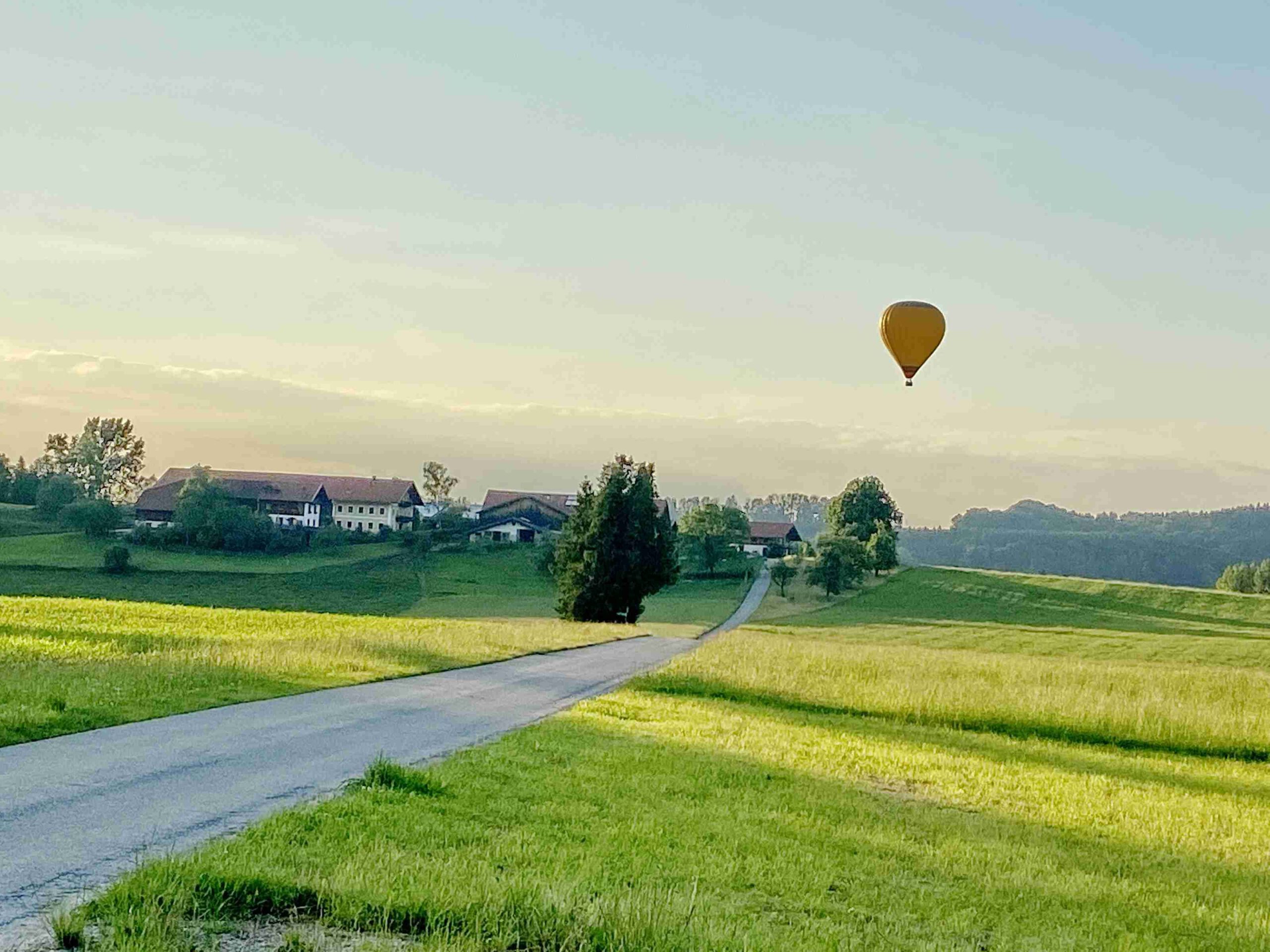 Gelber Heißluftballon schwebt über grüne Landschaft