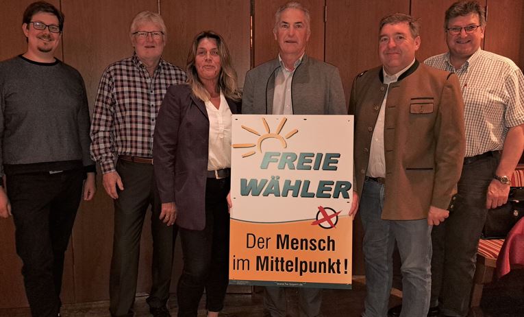 Vorstandschaft der Freien Waehler Rosenheim stehend mit Plakat der Freien Waehler