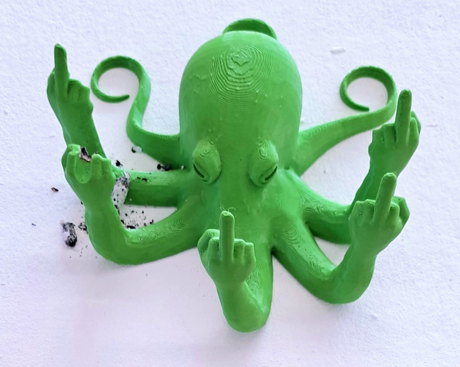 Grüner Oktopus zeigt mit allen Armen Stinkefinger, neben sich Zigarretenasche