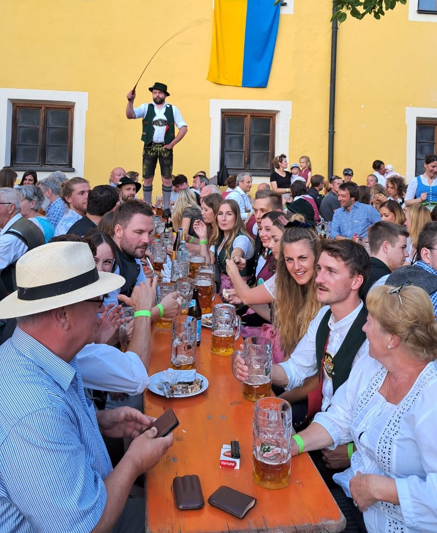 Klosterfest Kloster Reisach mit Goasslschnalzer auf dem Tisch ganz hinten vor der gelben Klostermauer