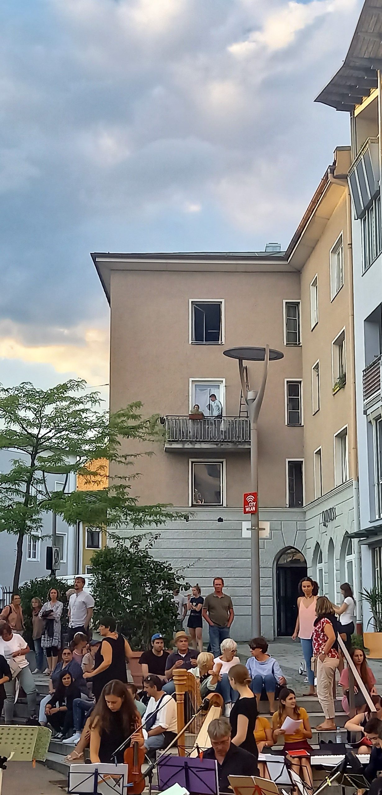 Klassik-Open-Air am Salzstadel -Orchester vor Häusern, bei denen Bewohner auf dem Balkon stehen und lauschen