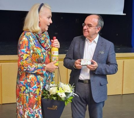 Gabriele Bauer links mit einer Flasche Eierlikör und Blumen und Karl-Heinz Brauner, Vorstand des Historischen Vereins Rosenheim rechts