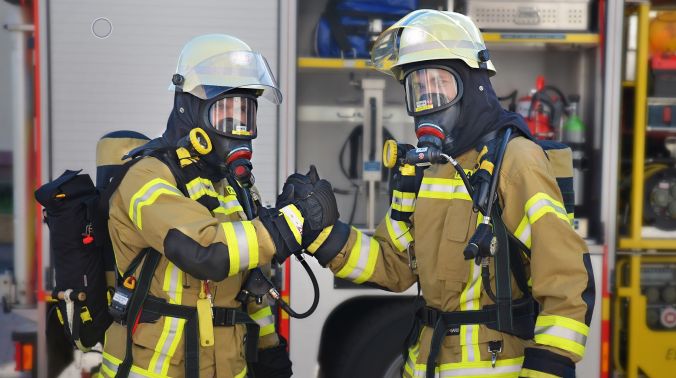 Zwei Feuerwehrmänner in Montur reichen sich die Hand