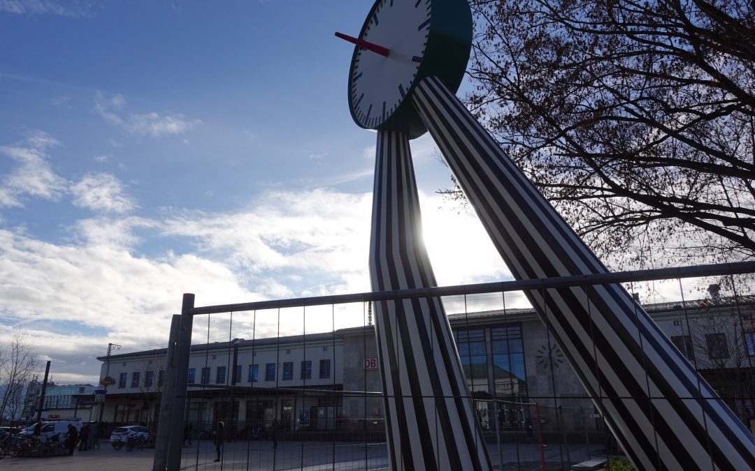 Eine Uhr auf zwei Beinen am Bahnhof