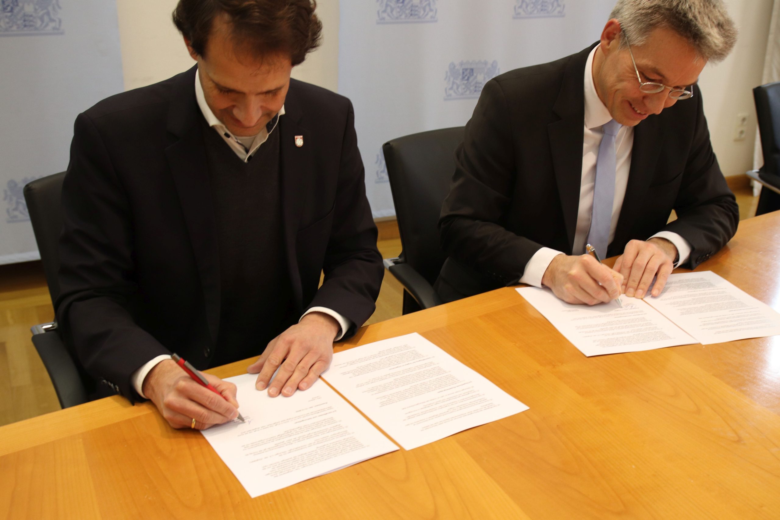 Rosenheims Oberbürgermeister Andreas März und Landrat Otto Lederer beim Unterzeichnen der Verträge