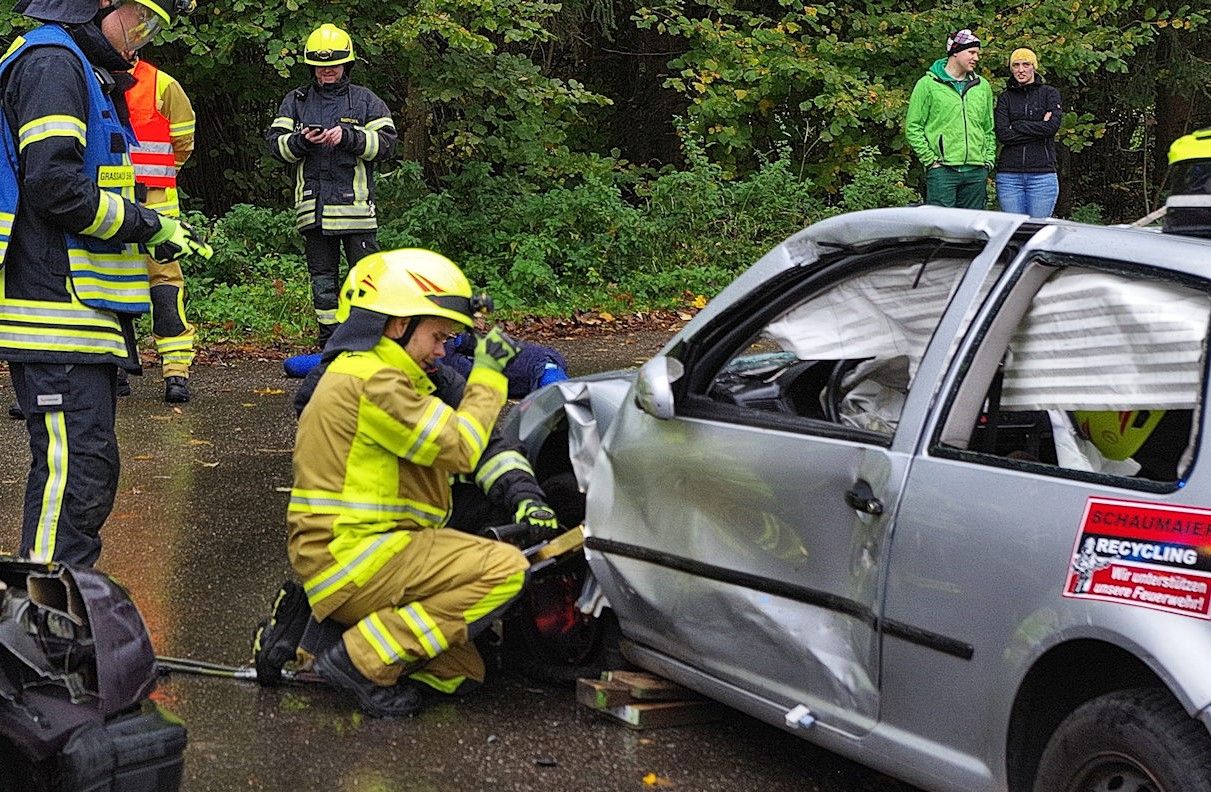 Zwei Feuerwehrler üben den Einsatz an einem kaputten Auto