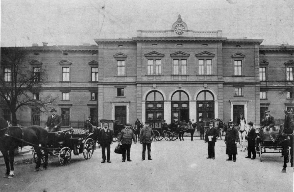 Kutschen und Menschen vor dem alten Rosenheimer Bahnhof in der Zeit um 1870