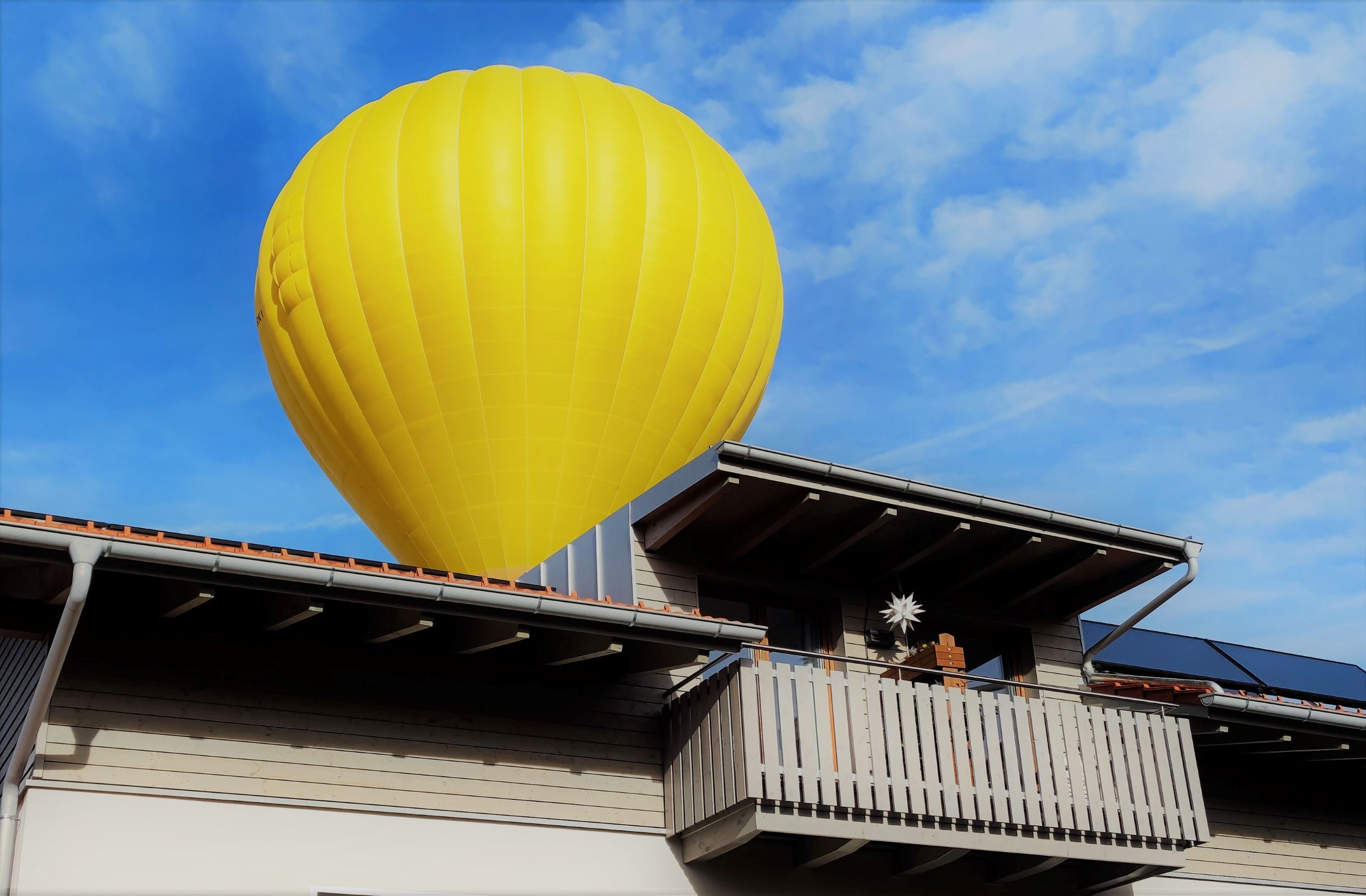 Gelber Heißluftballon knapp über Hausdach