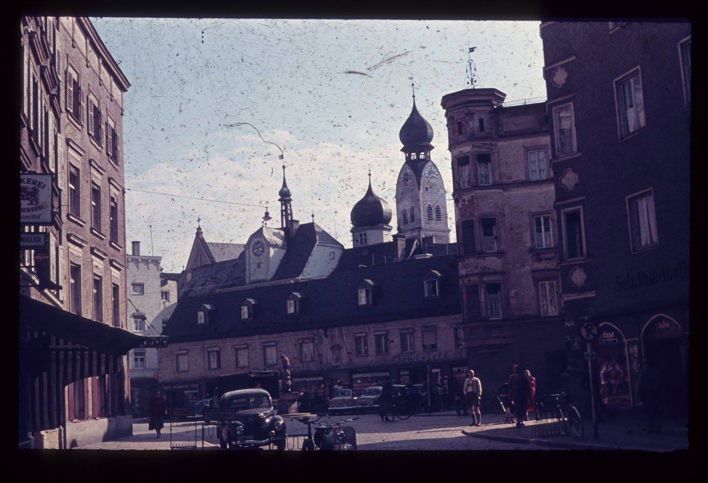 Der Rosenheimer Ludwigsplatz zur Sommerzeit im Jahr 1954 mit Passanten und Fahrzeugen passend zur Zeit