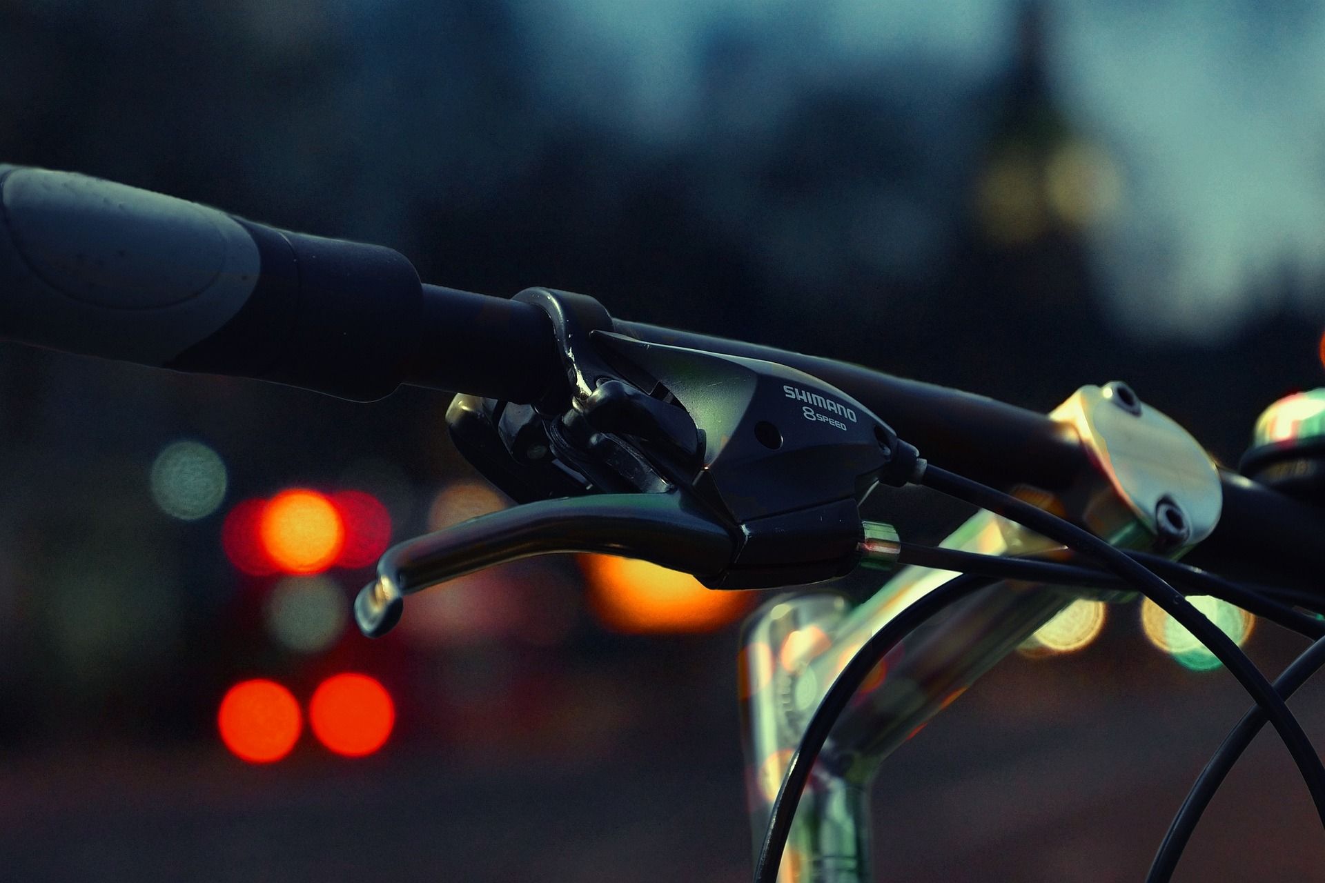 Blick über Fahrradlenkstange hin zu verschwommene Szene mit Lichtern in der Dunkelheit