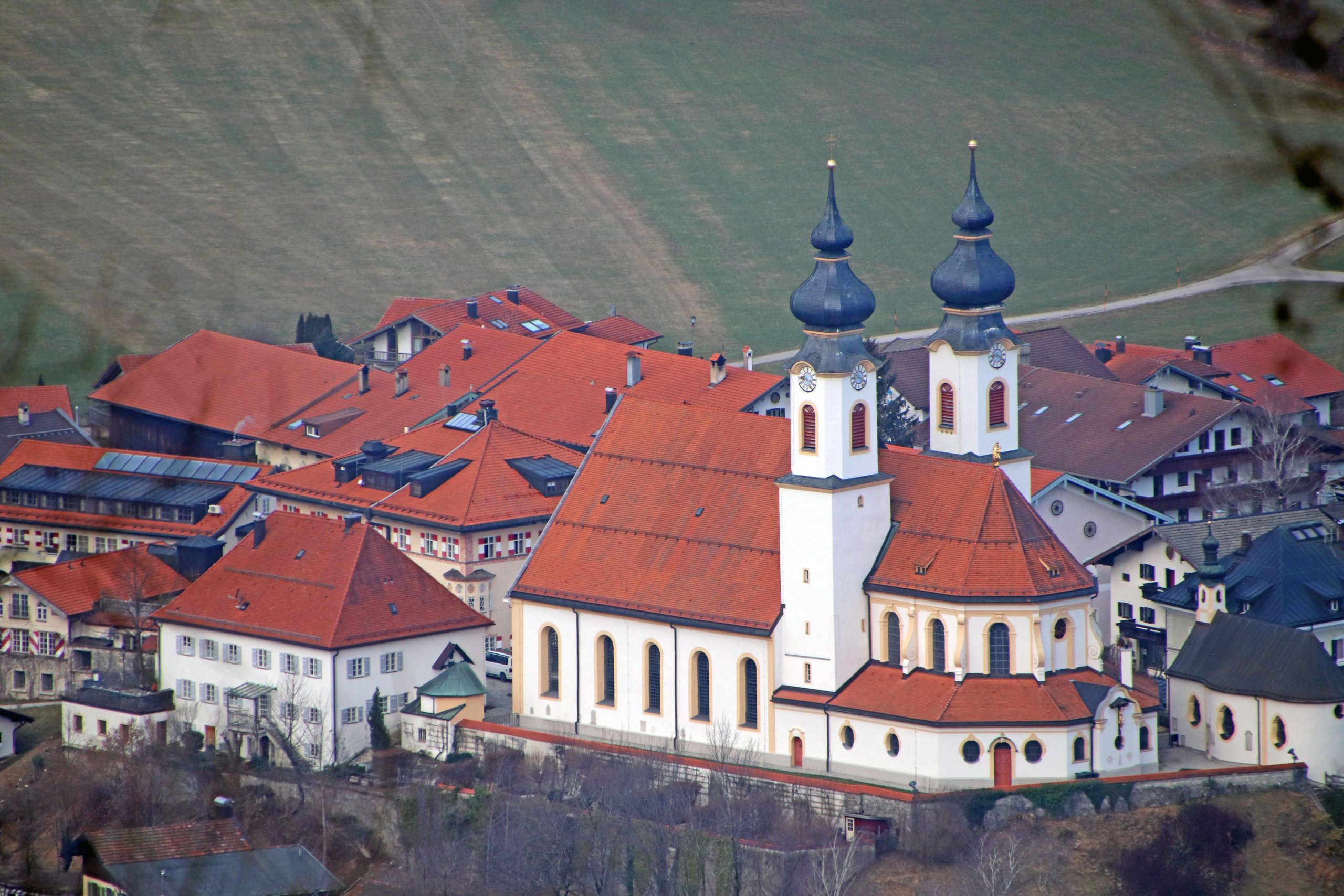 Bick auf Aschauer Pfarrkirche "Darstellung des Herrn" in Aschau im Chiemgau fotografiert von einem Hügel aus.