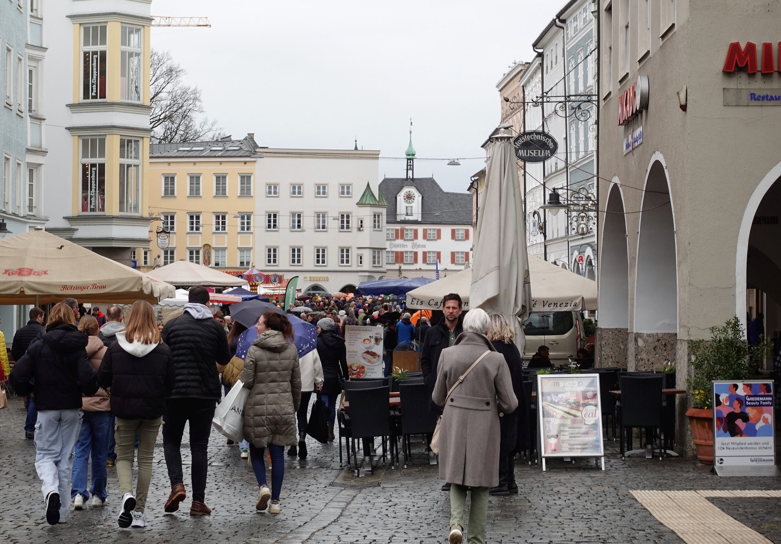 Besucher, teils mit Regenschirm, auf dem Max-Josefs-Platz Rosenheim beim Frühlingsmarkt