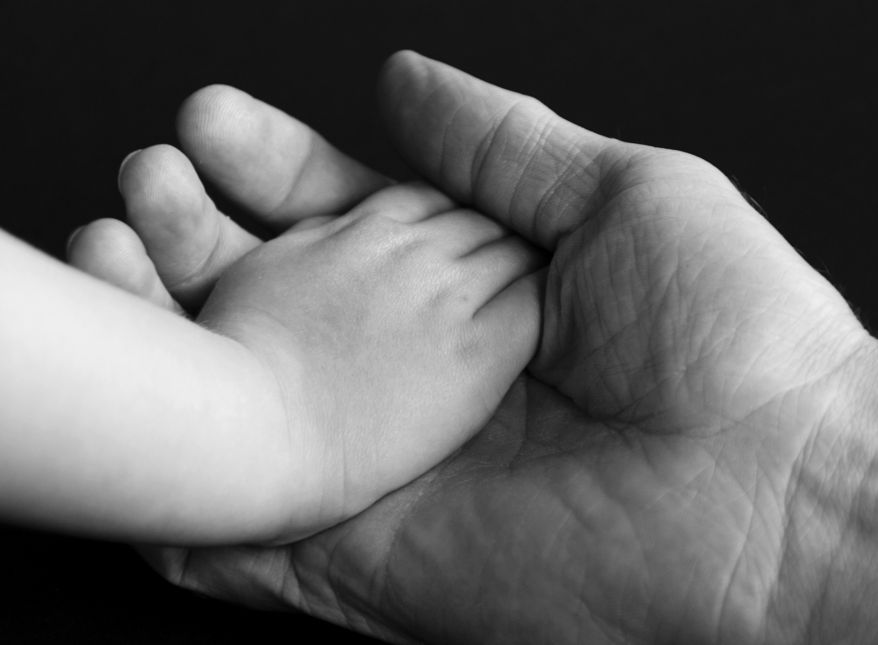 Kinderhand in Männerhand. Schwarz-Weiss-Foto