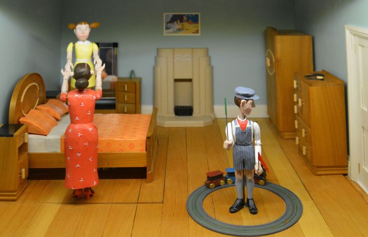 Blick in ein Puppenhaus - Szene Kinderzimmer Mama spielt mit Tochter. Sohn steht in Eisenbahnring
