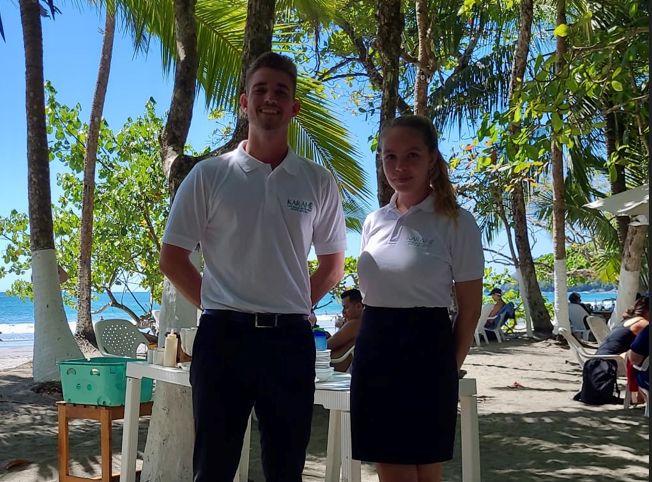Zwei Auszubildende der Berufsfachschule für Hotel- und Tourismusmanagement Traunstein in Costa-Rico vor Palmen und Meer