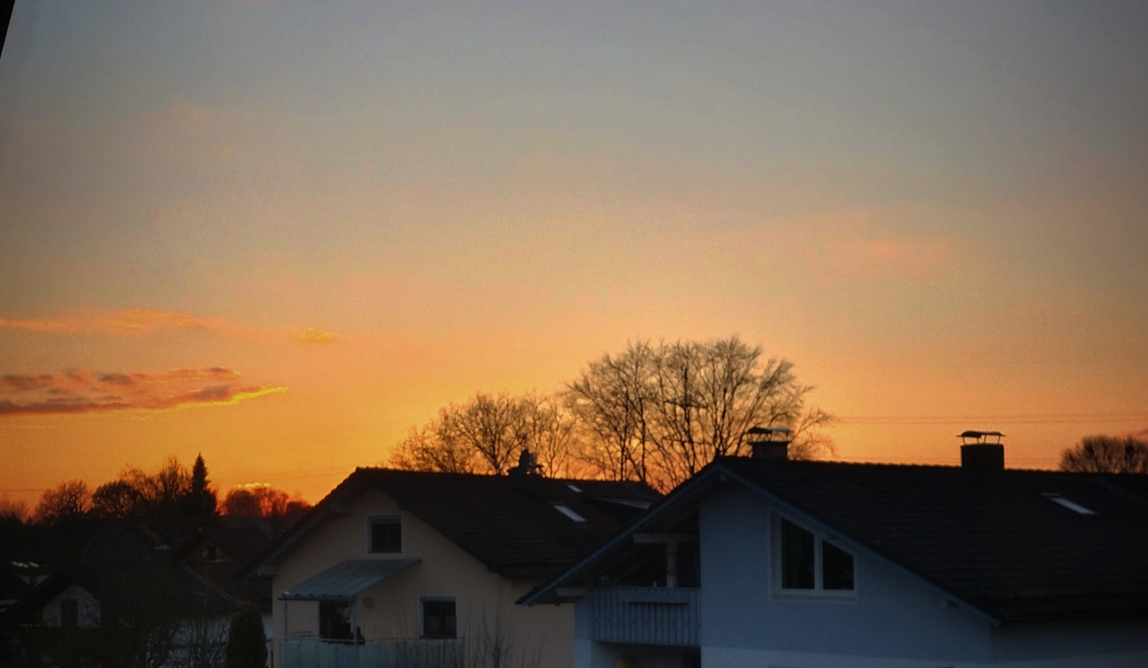 Goldgelber Sonnenaufgang, davor Häuser.
