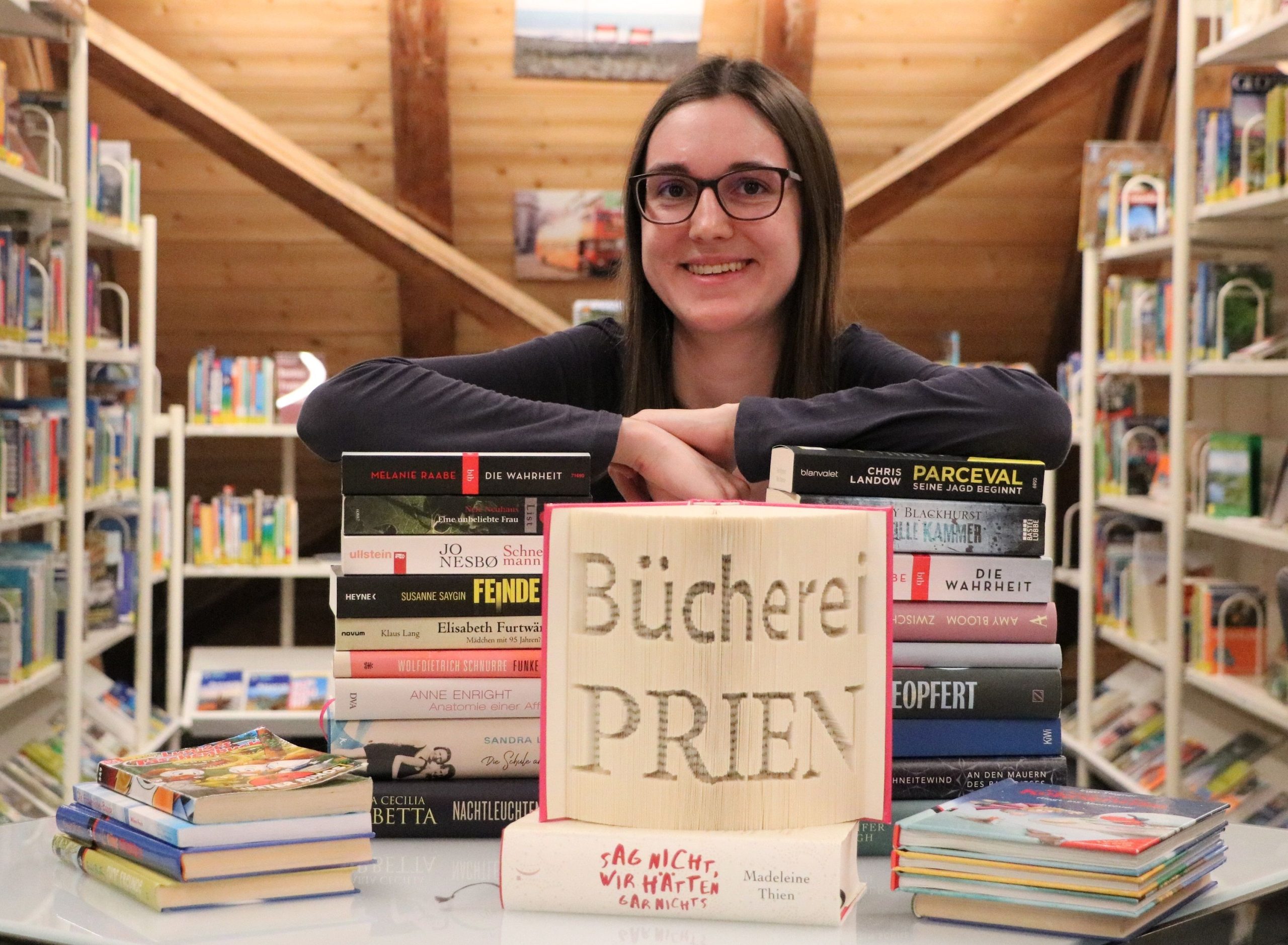 Melanie Scheiber, Leiterin der Bücherei Prien am Chiemsee mit vielen Büchern. Foto: Prien Marketing GmbH