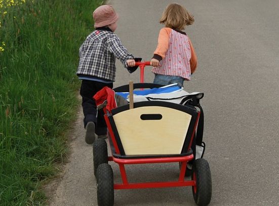Zwei Kinder ziehen Bollerwagen