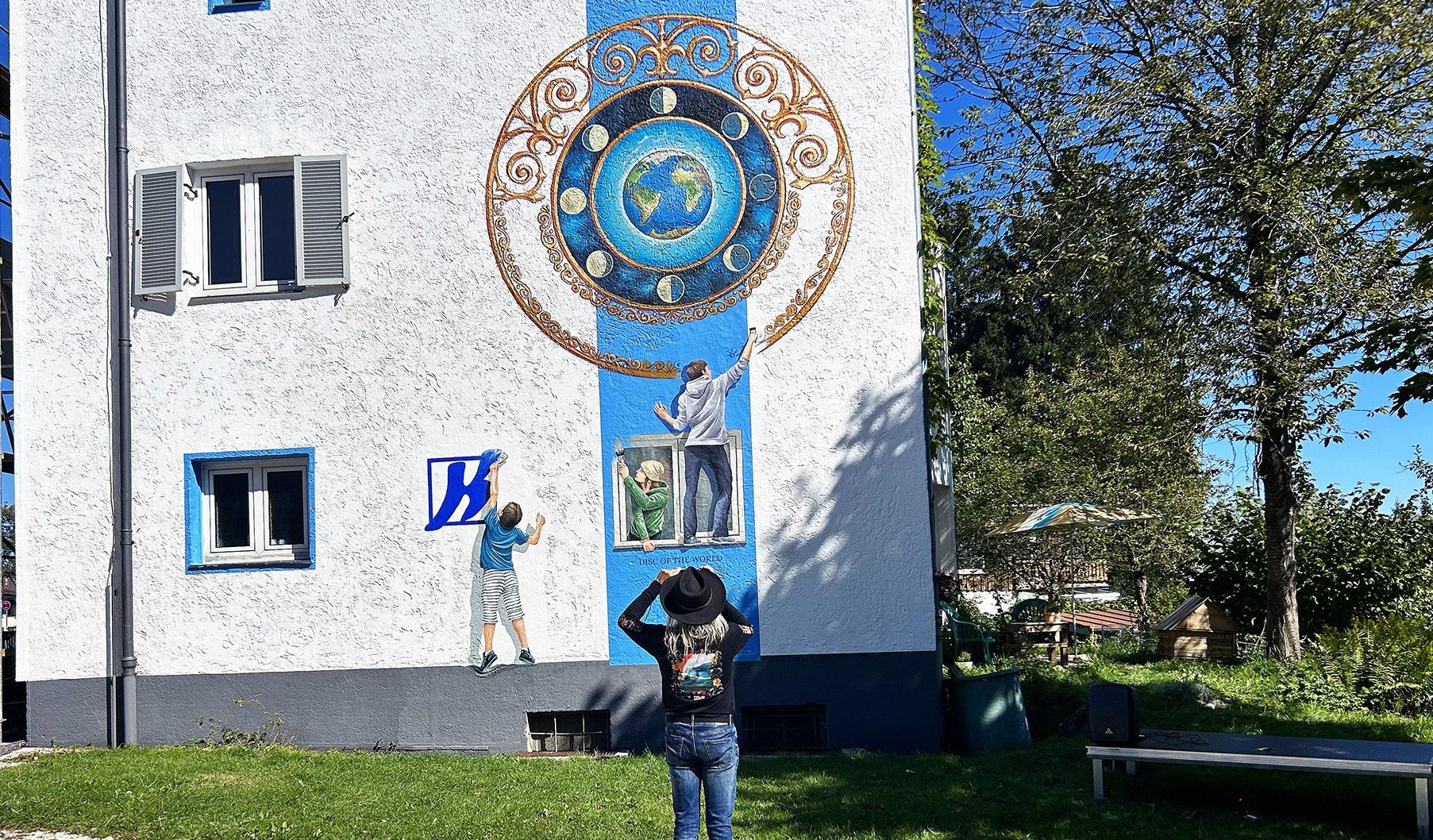 Künstler Georg Huber vor seinem Kunstwerk "Disc of the World" an der Fassade der Privatschule Dr. Kalscheuer in Traunstein. Foto: Privatschule Dr. Kalscheuer