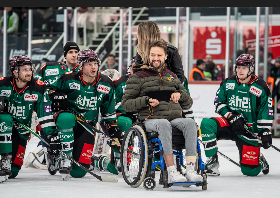 Mike Glemser im Rollstuhl mit Starbulls-Spielern auf dem Eis. Foto: Copyright Peter Lion Ludwig Schirmer