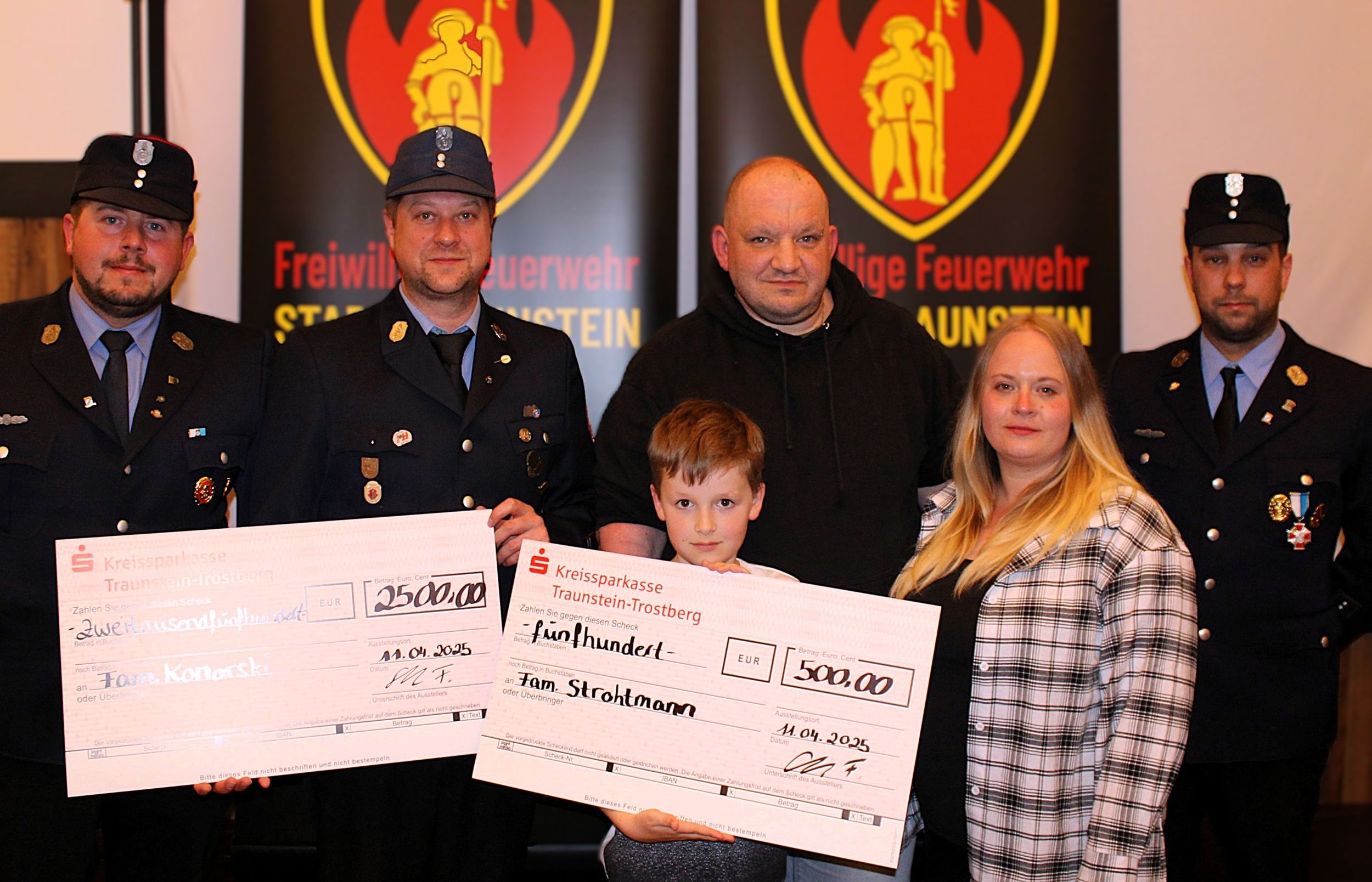 Spende aus der Aktion Christbaum Traunstein Thomas Konarski und Sascha Strothmann seine Lebensgefährtin Vicky und sein Sohn Elias durften jeweils einen Spendenscheck aus dem Erlös der Aktion Christbaum entgegennehmen. Robert Oettl (links) und Florian Scholz (rechts) haben den Scheck stellvertretend für die beteiligten Feuerwehren Haslach, Kammer, Traunstein, Surberg und Wolkersdorf übergeben. Copyright Kreisfeuerwehrverband Traunstein