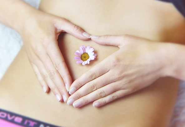 Bauch Hände auf Bauch, Gänseblümchen auf Bauchnabel. Foto: re