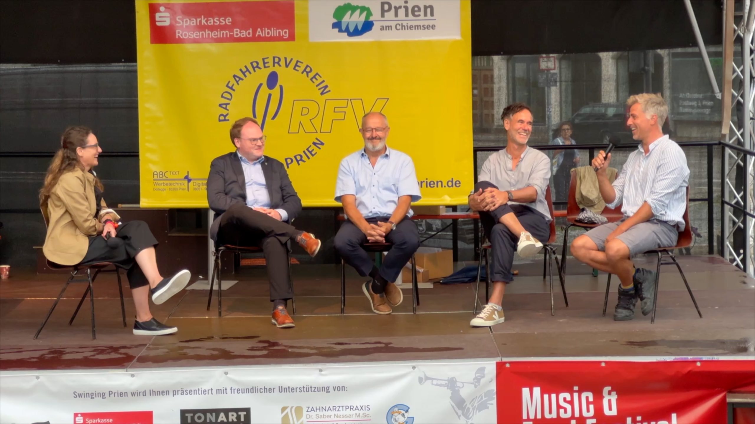 2025-07-06 Pressebild Podiumsdiskussion Fahrradstraßen c-Markt Prien a. Chiemsee Podiumsdiskussion „Fahrradstraßen – eine Chance für Prien?“: (von links): Erster Bürgermeister Andreas Friedrich, sein Kolbermoorer Amtskollege Peter Kloo sowie die beiden Fahrradbeauftragten der Gemeinde Prien, August Pflugfelder und Max Kölbl, diskutieren unter der Moderation von Anna Karina Schlemer (im Bild links außen) mit zahlreichen Bürgerinnen Bürger zum Thema. Foto: Copyright Anita Berger