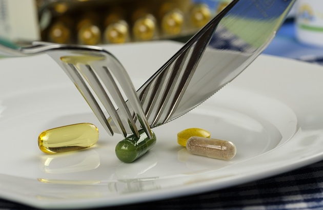 Tabletten Pillen werden mit Messer und Gabel auf weißem Teller gegessen. Foto: re